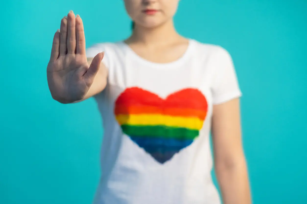 unrecognizable-woman-with-refusal-hand-gesture-in-rainbow-flag-heart-shirt