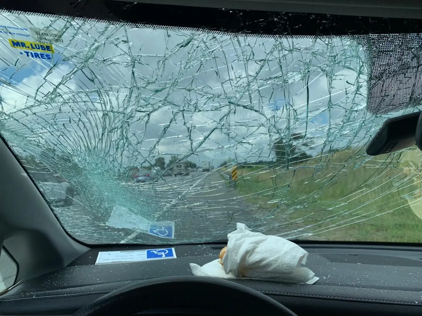 A broken windshield with a wheelchair accessible sign on the dashboard