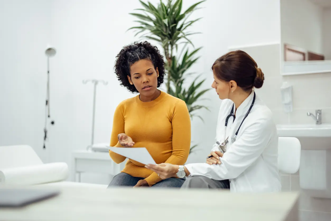 Female patient and doctor discussing potential risks of treatment in medical office.