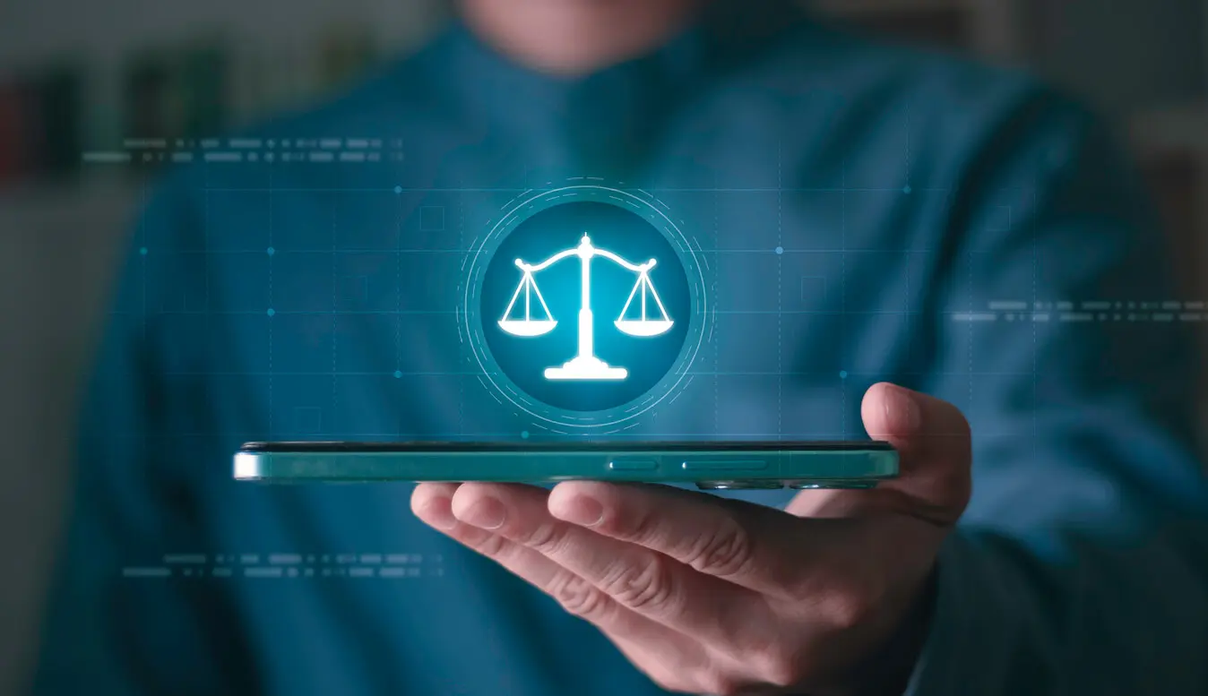 a person holds a cellphone with the scales of justice interface above it