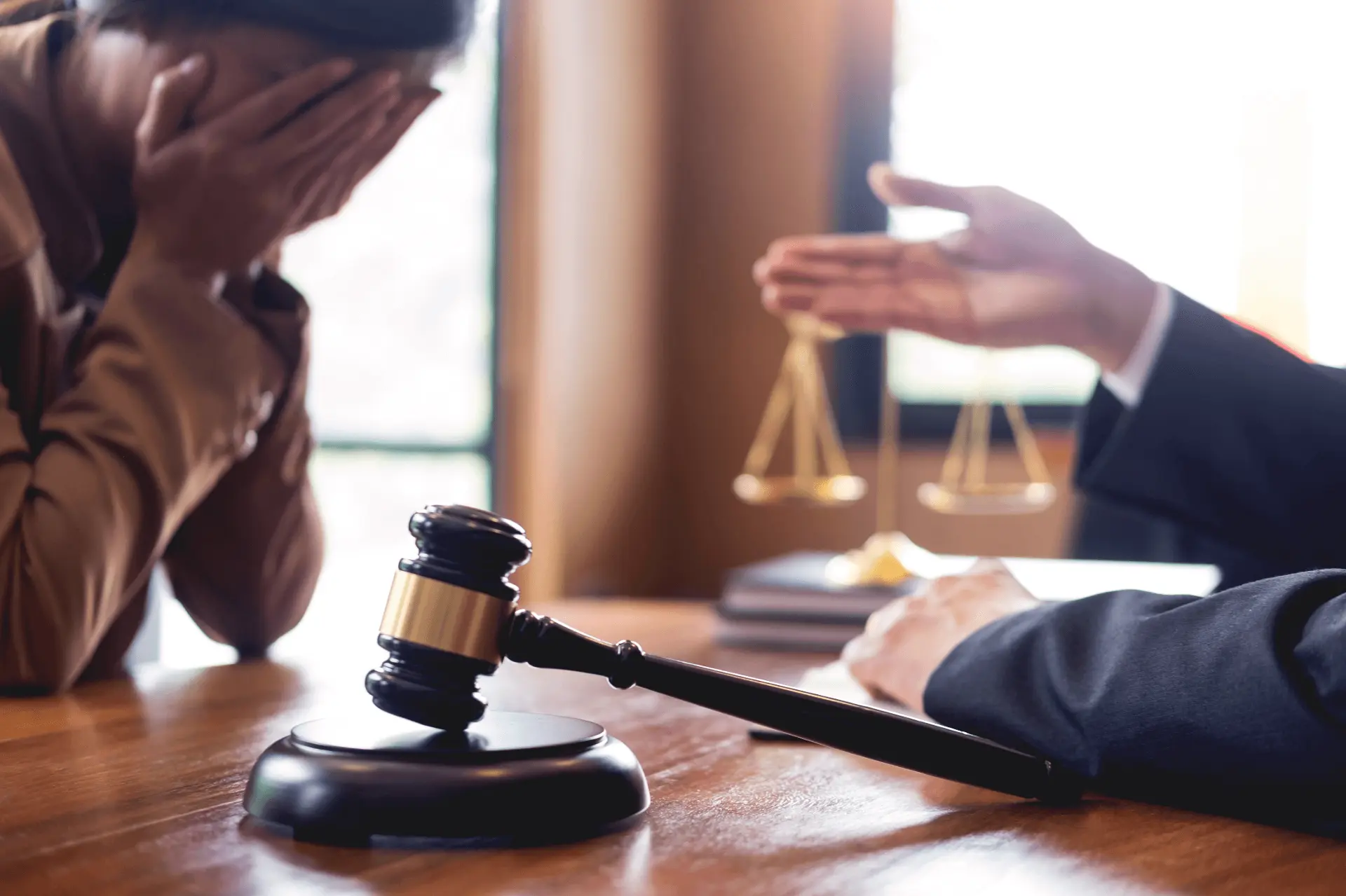 a woman puts her head in her hands in a courtroom in front of a judge