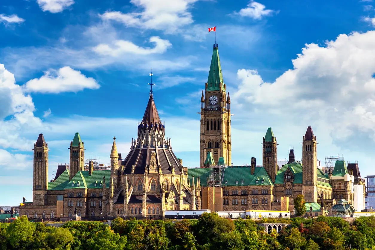 Canadian parliament building in Ottawa with Canadian flag blowing in the wind