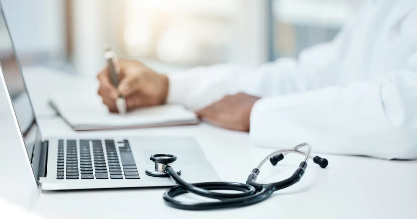a physician takes notes on a notepad in a hospital office