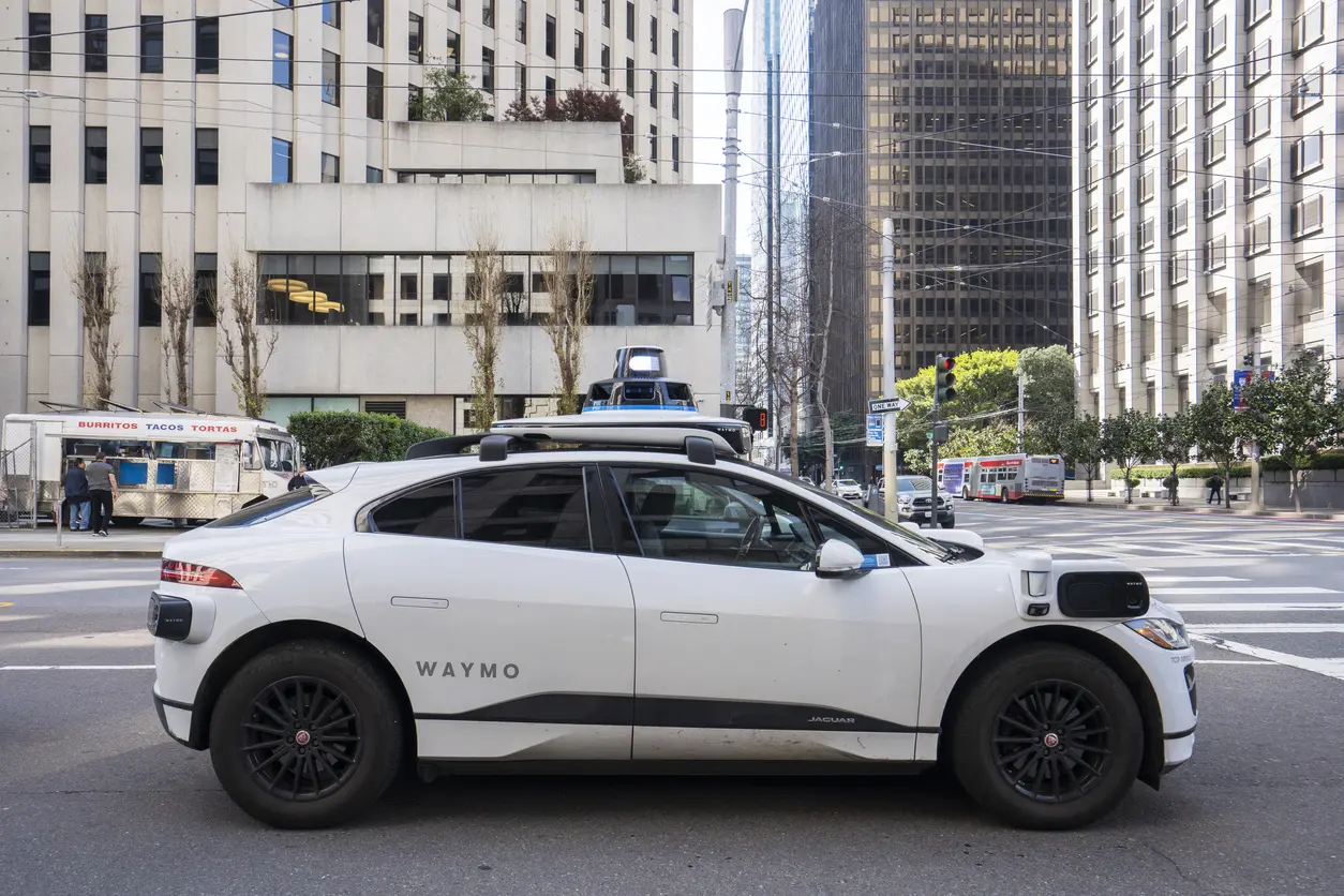 a Waymo waits at an intersection in a major city
