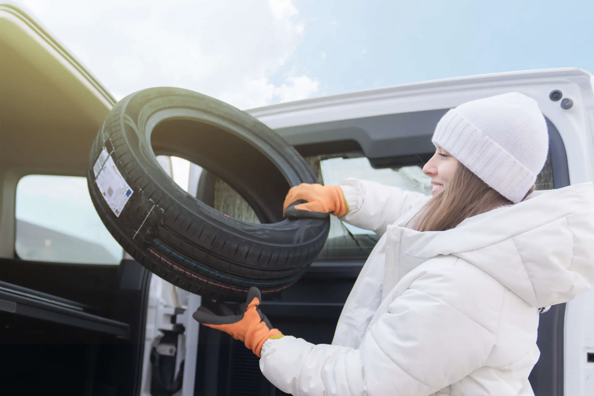 a woman replaces her tires with snow tires to prepare for the winter weather