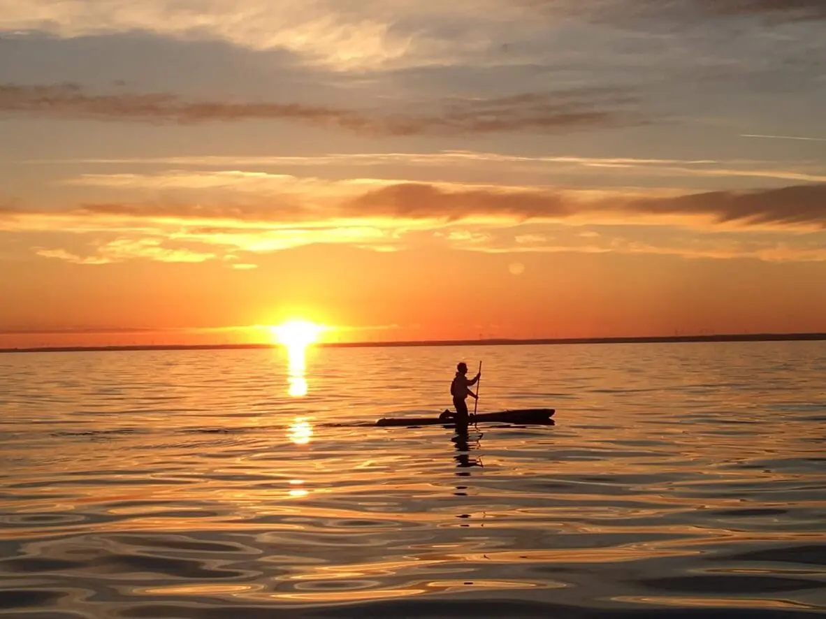 man-paddle-boarding-across-Lake-Huron-at-sunrise