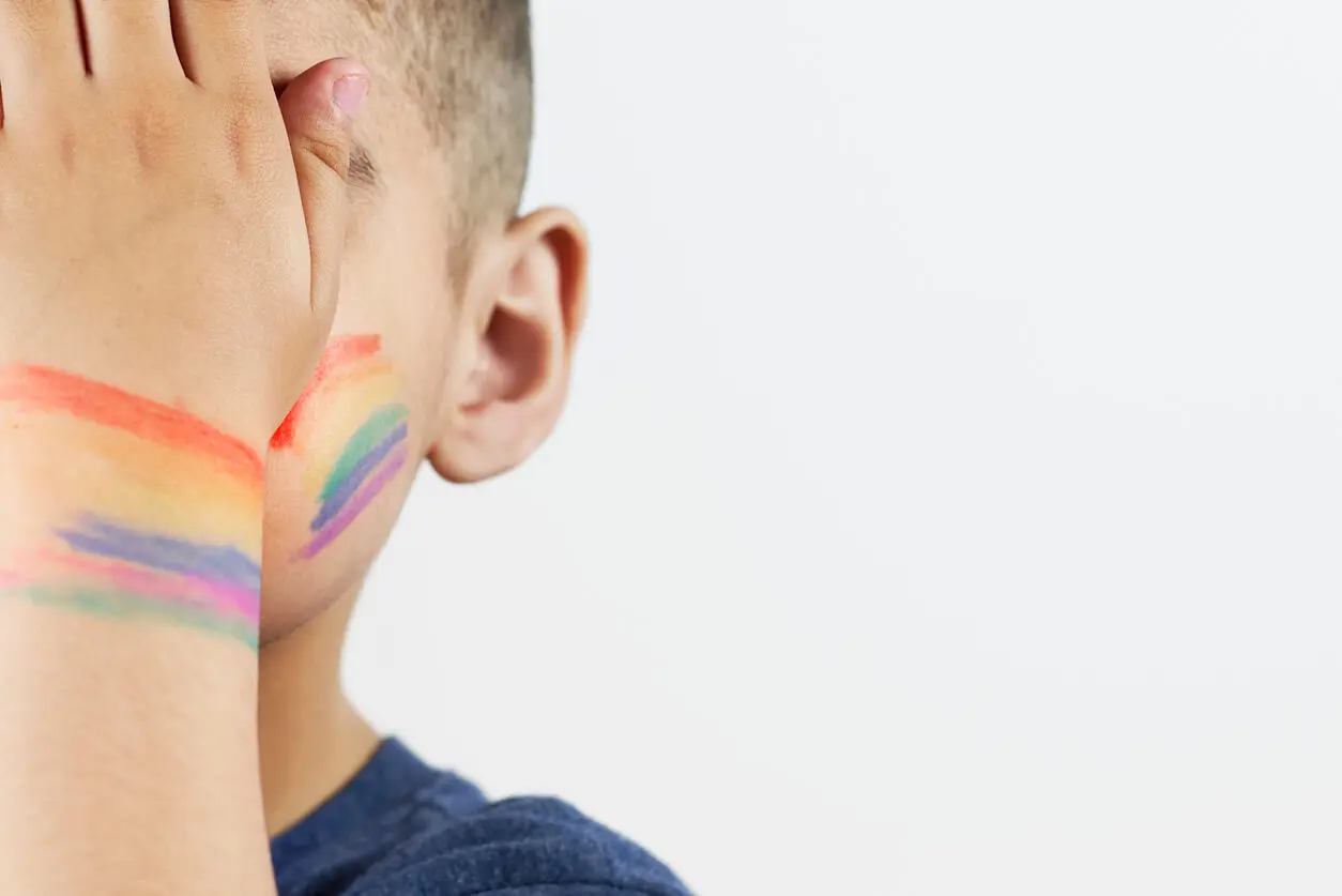 little-boy-covering-his-face-with-his-half-painted-rainbow-hand