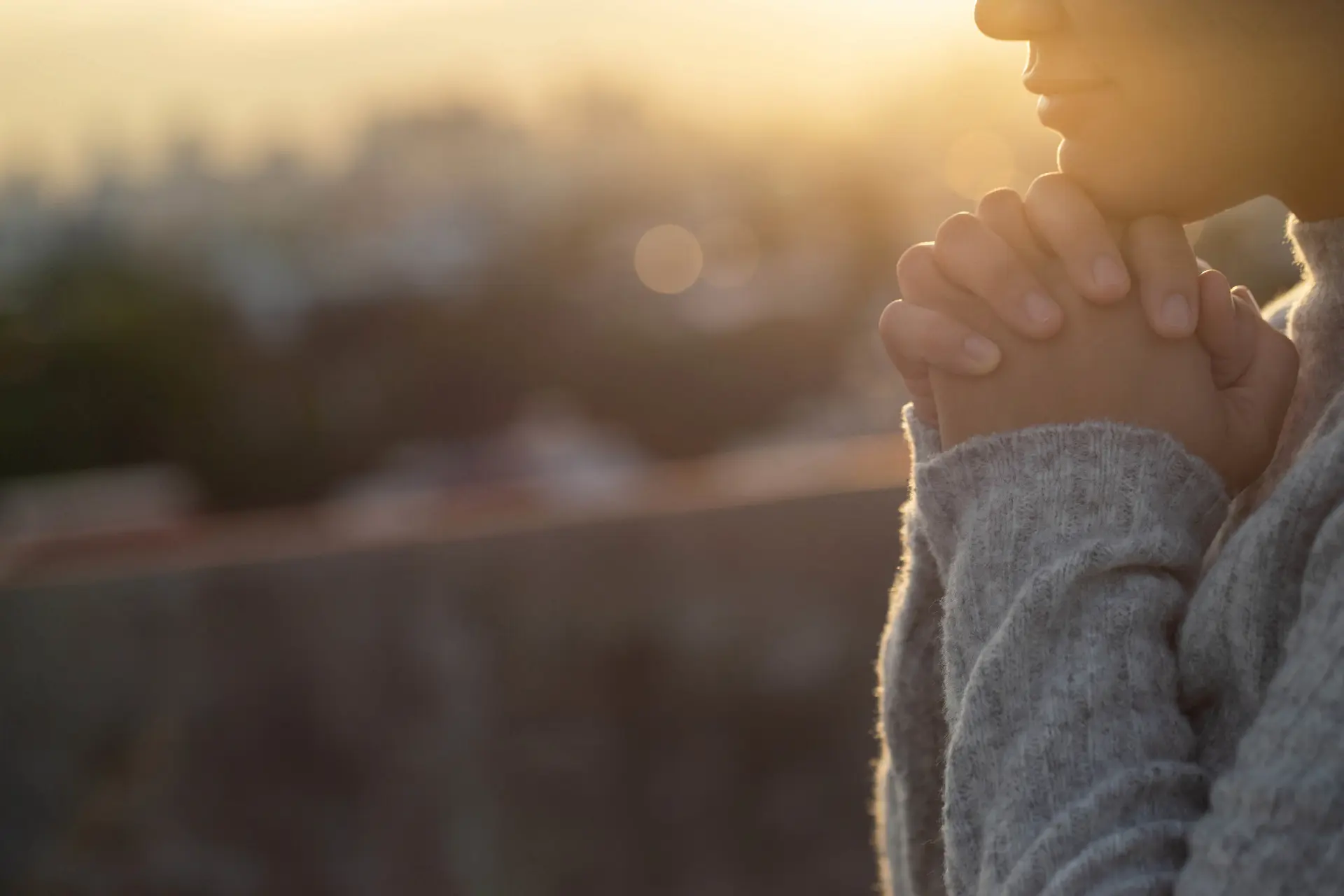 a potential survivor of sexual abuse wearing a grey sweater stands with their palms together as they contemplate their options moving forward