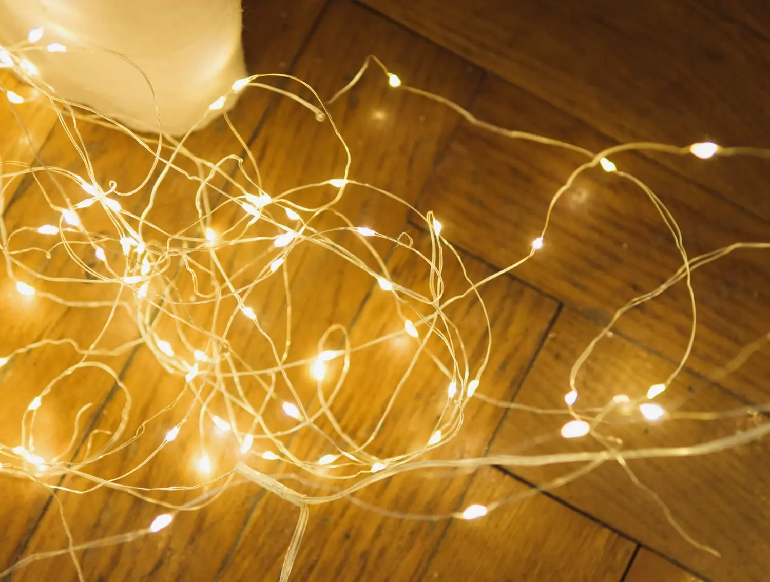 faulty string lighting tangled on hardwood floor of a bedroom