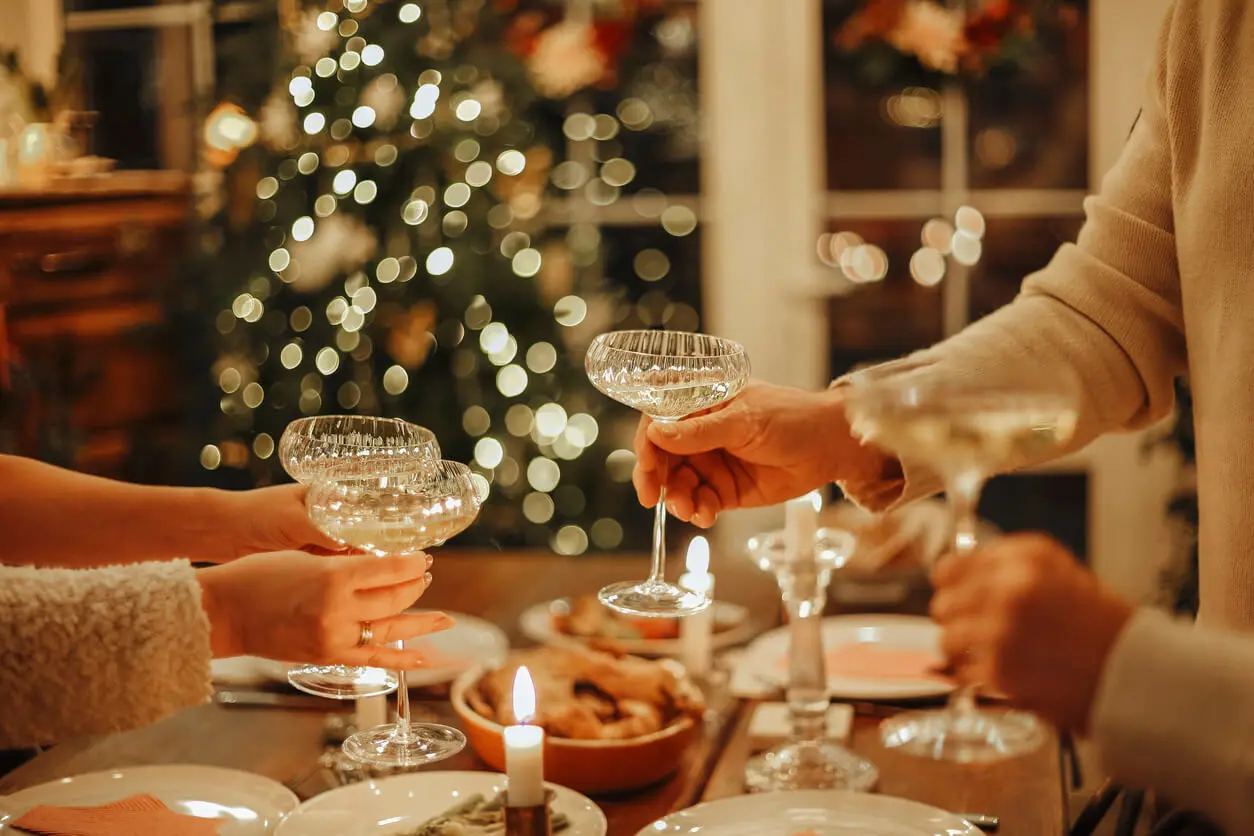 Friends and colleagues clink their champagne glasses while celebrating at a holiday party