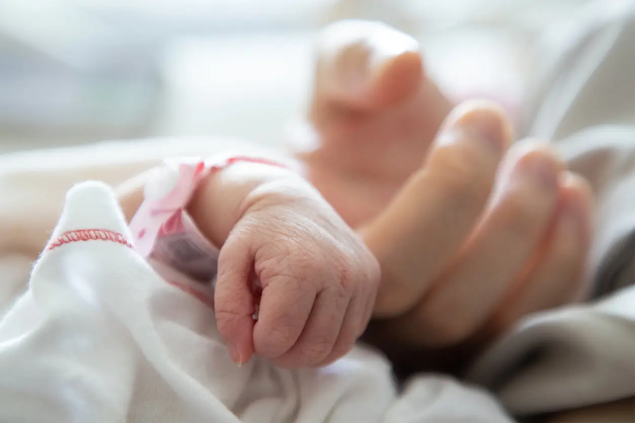 Premature baby in NICU holding mother's finger