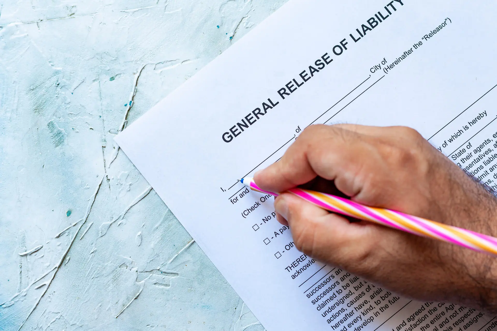 a person uses a pink and orange striped pen to sign a liability waver to take part in a sport or activity