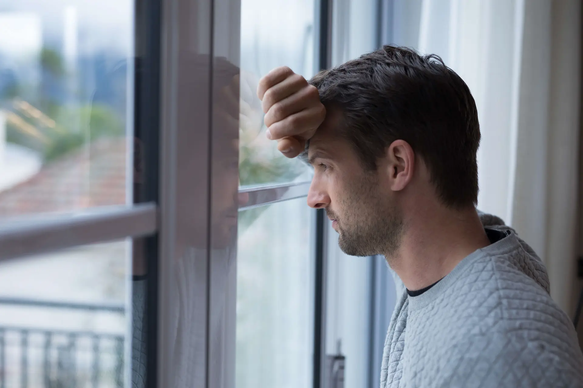 a person who may be a survivor of sexual abuse looks out of a window, deep in thought about what they might need to know about abuse suffered