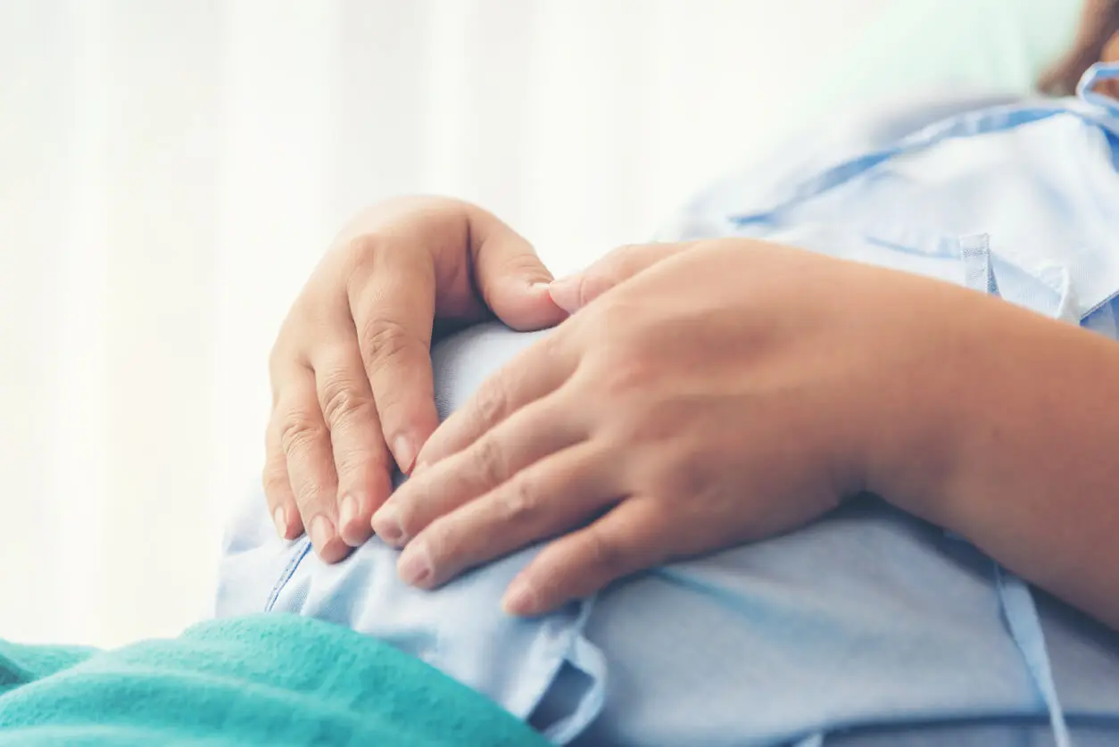 Pregnant woman holds onto her stomach while preparing for the stages of labour and delivery.