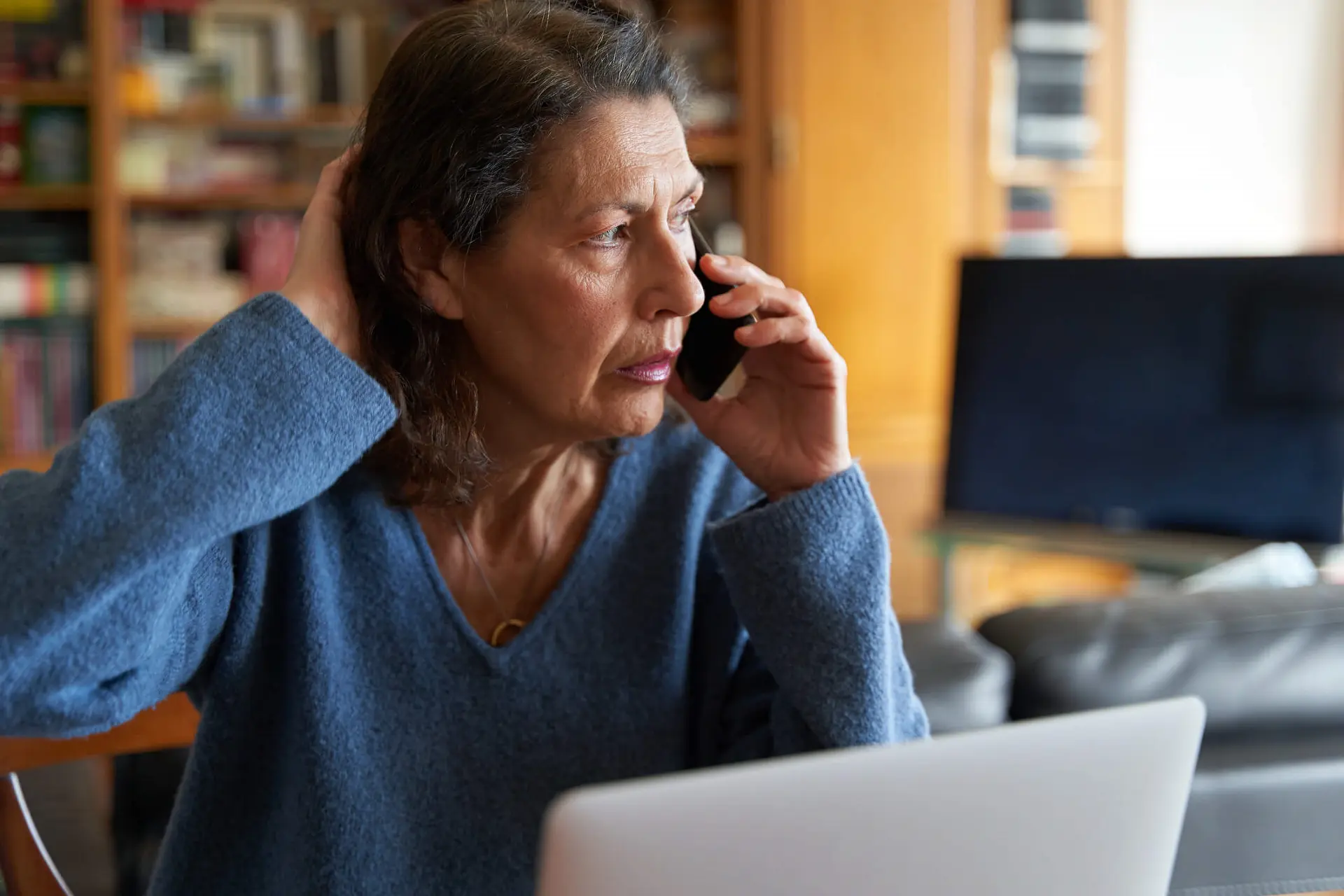 a woman in a blue v neck sweater calls a personal injury lawyer after her loved one has suffered an injury in a motor vehicle accident