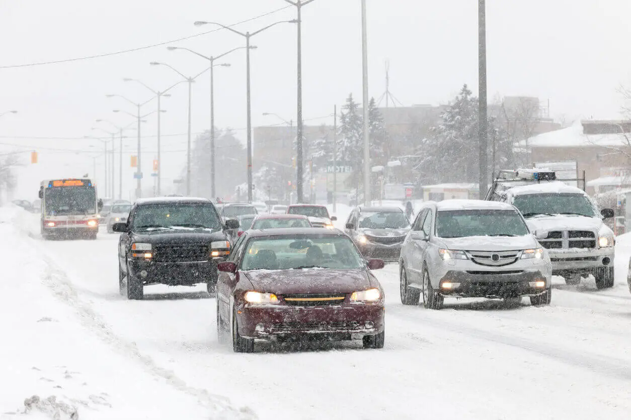 Vehicles carefully navigate through winter storm on snowy and icy roads.
