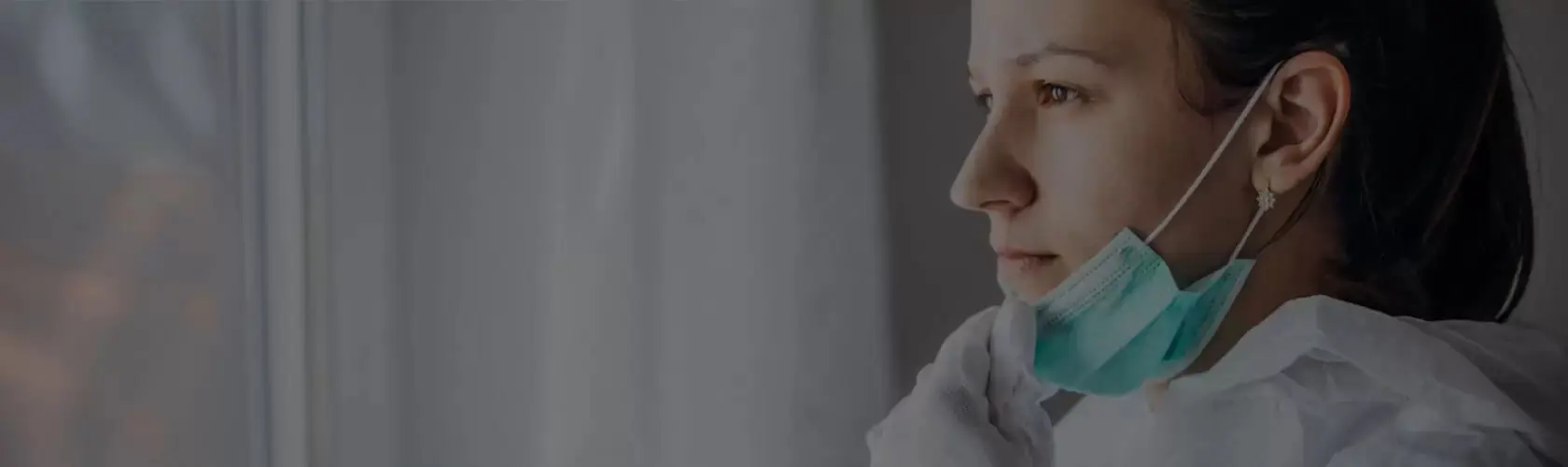 Close up of person looking out window with medical mask pulled down Close up of person looking out window with medical mask pulled down