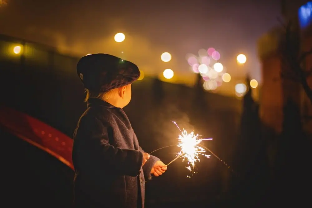 Photo of a child holding sparklers outside at night