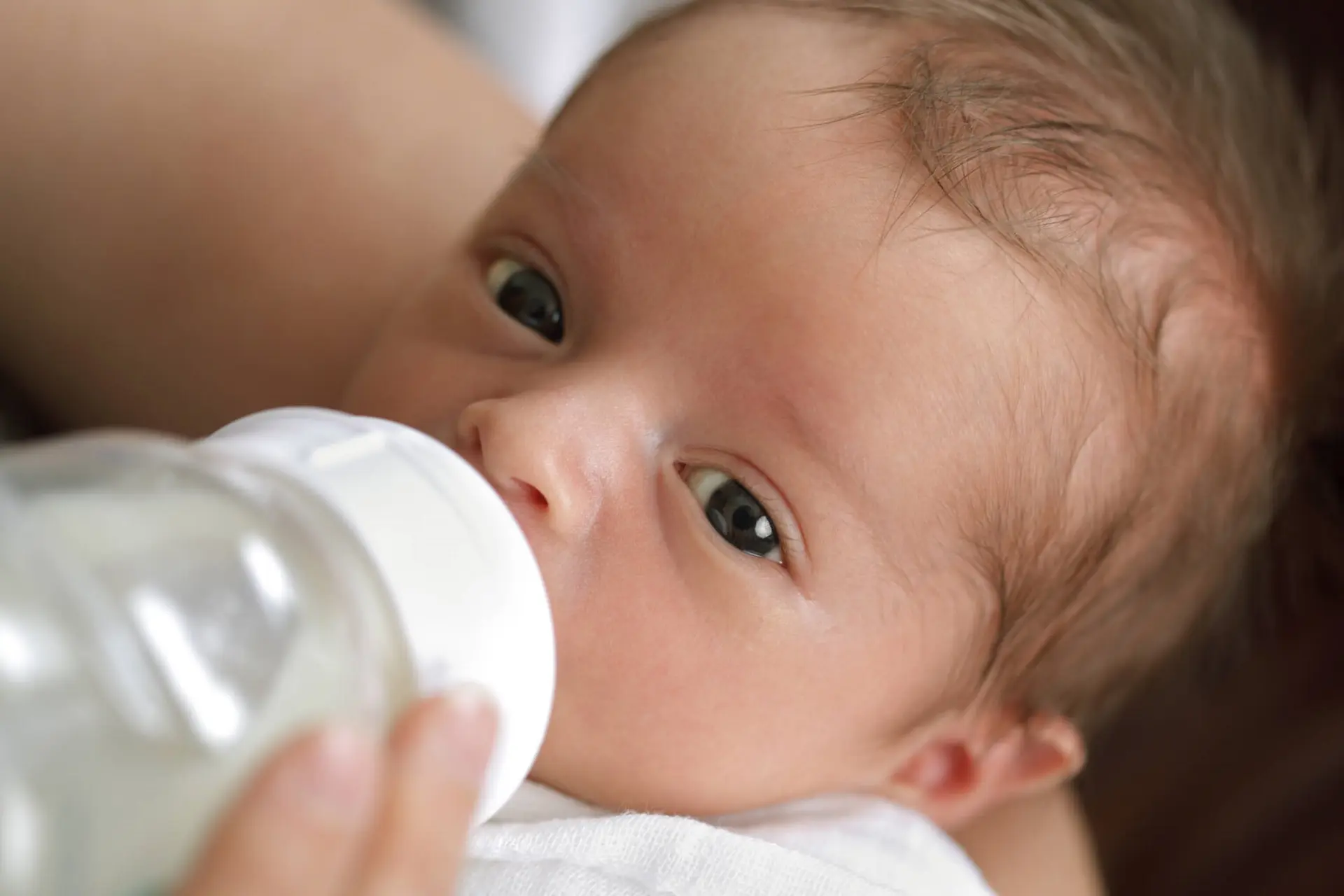 Mother holding her newborn baby boy and bottle feeding him.