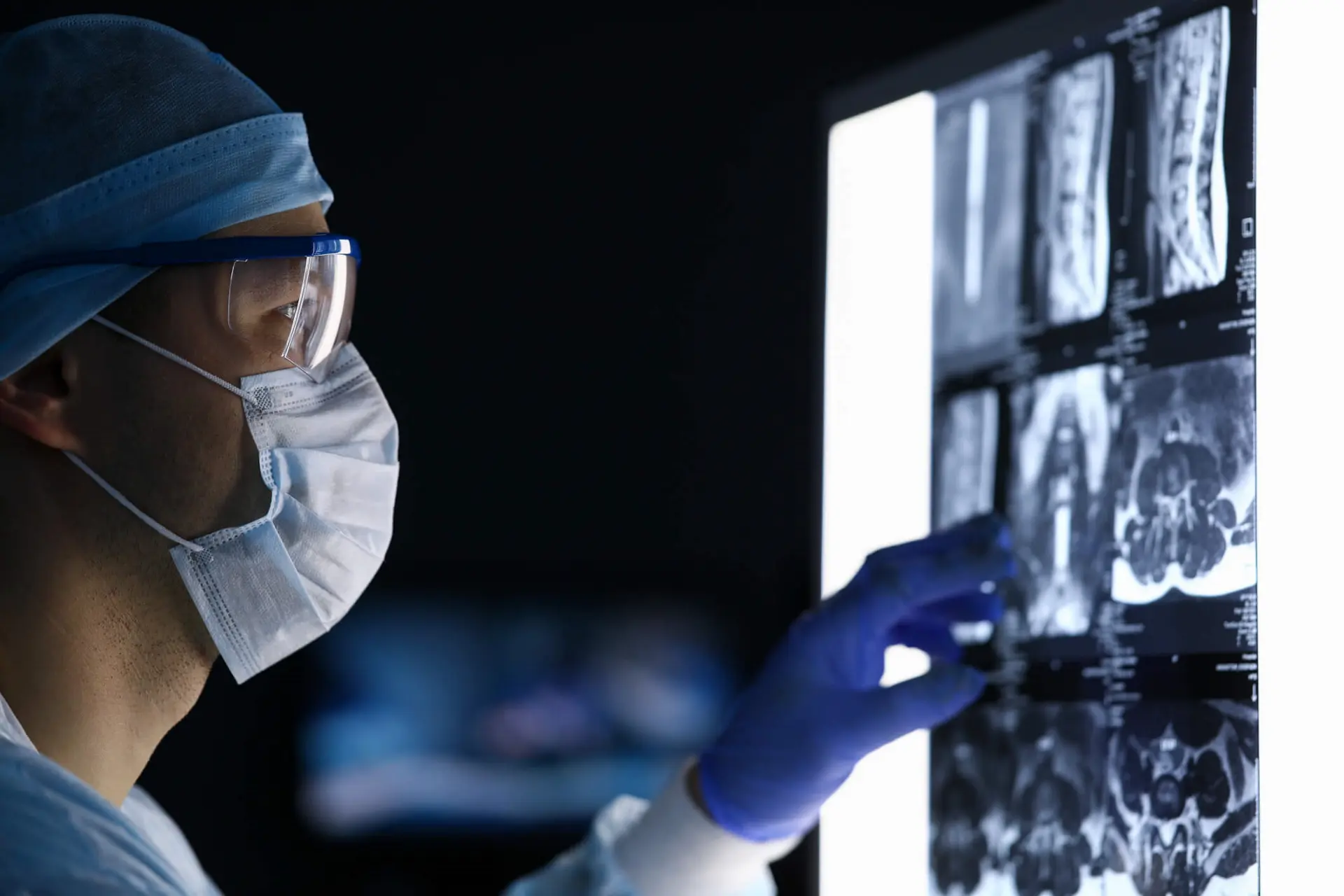 A male doctor in surgical gown reviewing MRI scans