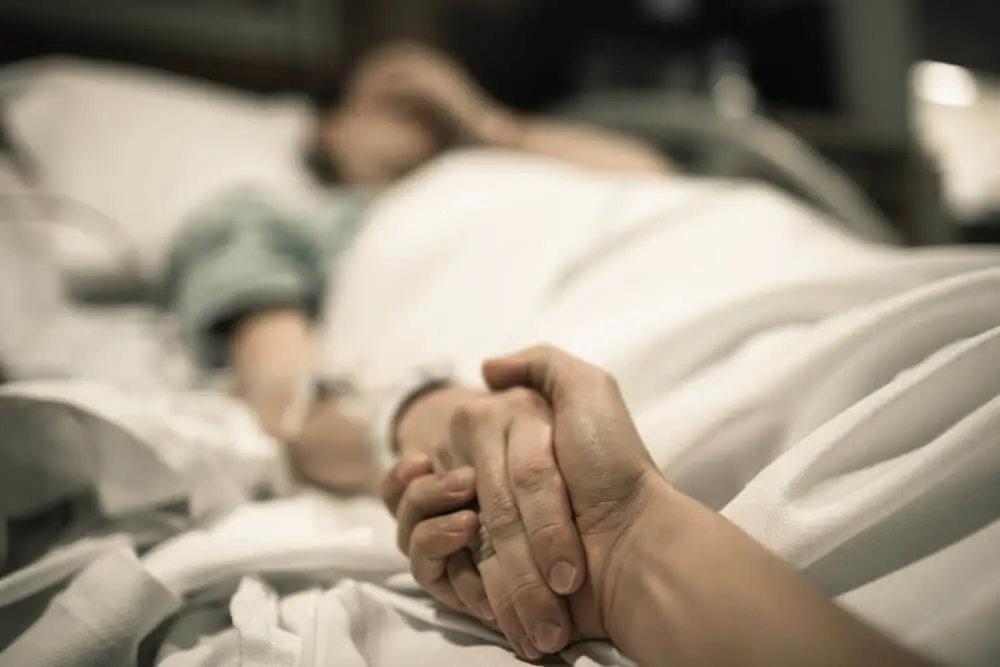 A caregiver comforts a patient in a hospital bed